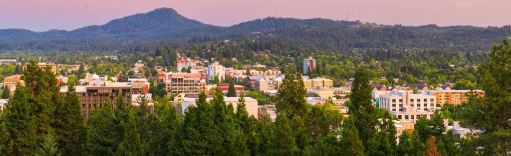 View of downtown Eugene, Oregon, with tree-lined neighborhoods and surrounding hills